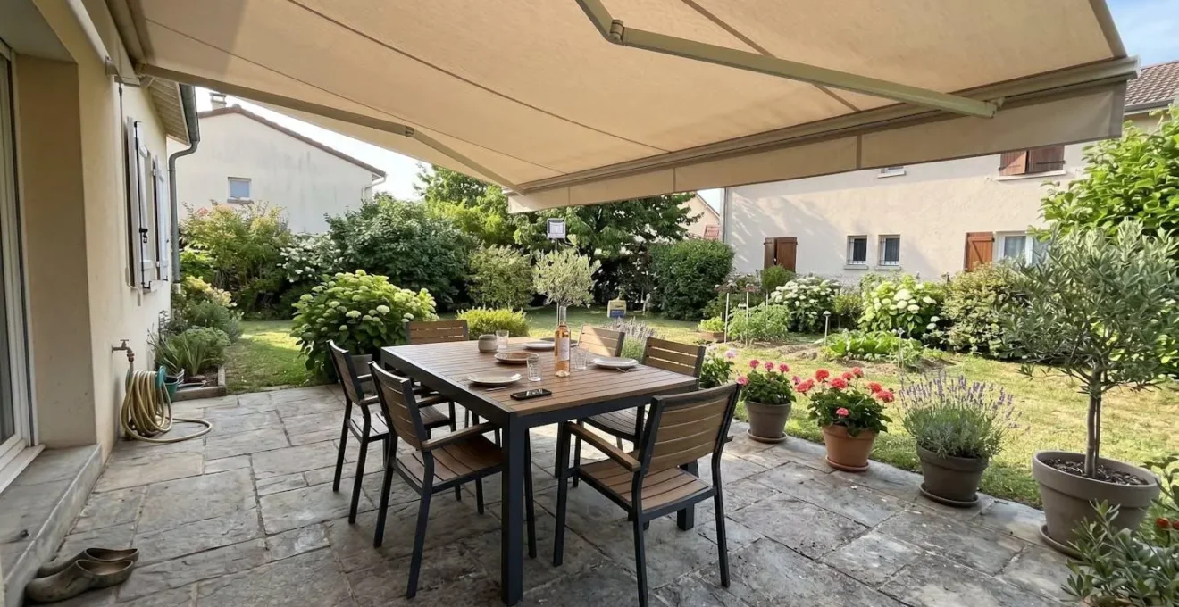 Terrasse contemporaine française avec store banne déployé au-dessus d'un salon de jardin sous lumière naturelle d'après-midi