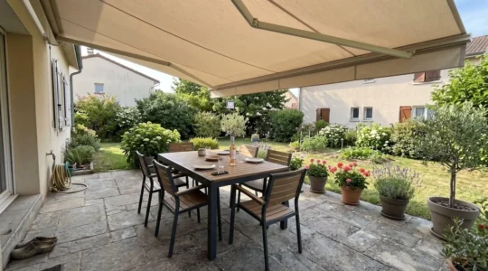 Terrasse contemporaine française avec store banne déployé au-dessus d'un salon de jardin sous lumière naturelle d'après-midi