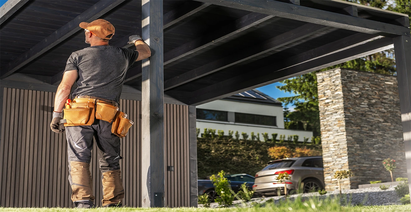 Professionnel installant une structure de carport double en aluminium devant une maison française